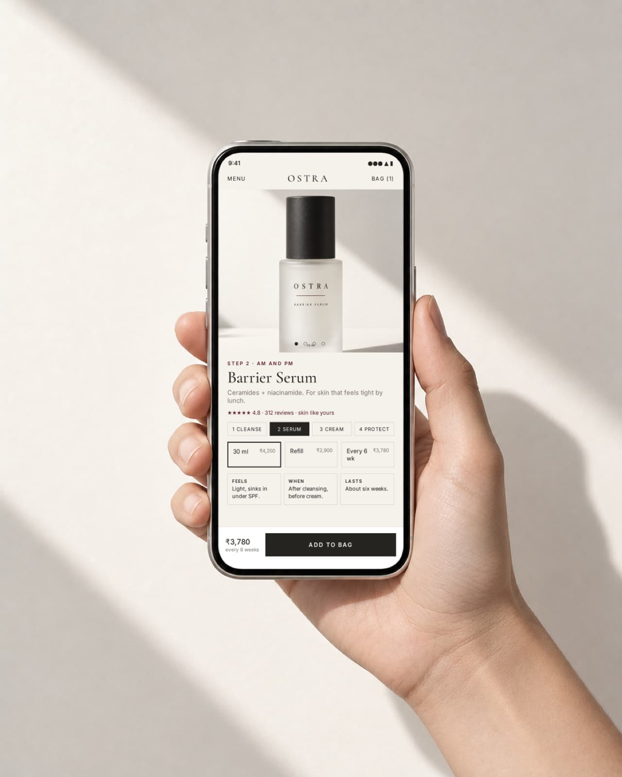 A hand holding a phone showing the OSTRA product page concept with the add-to-bag action visible