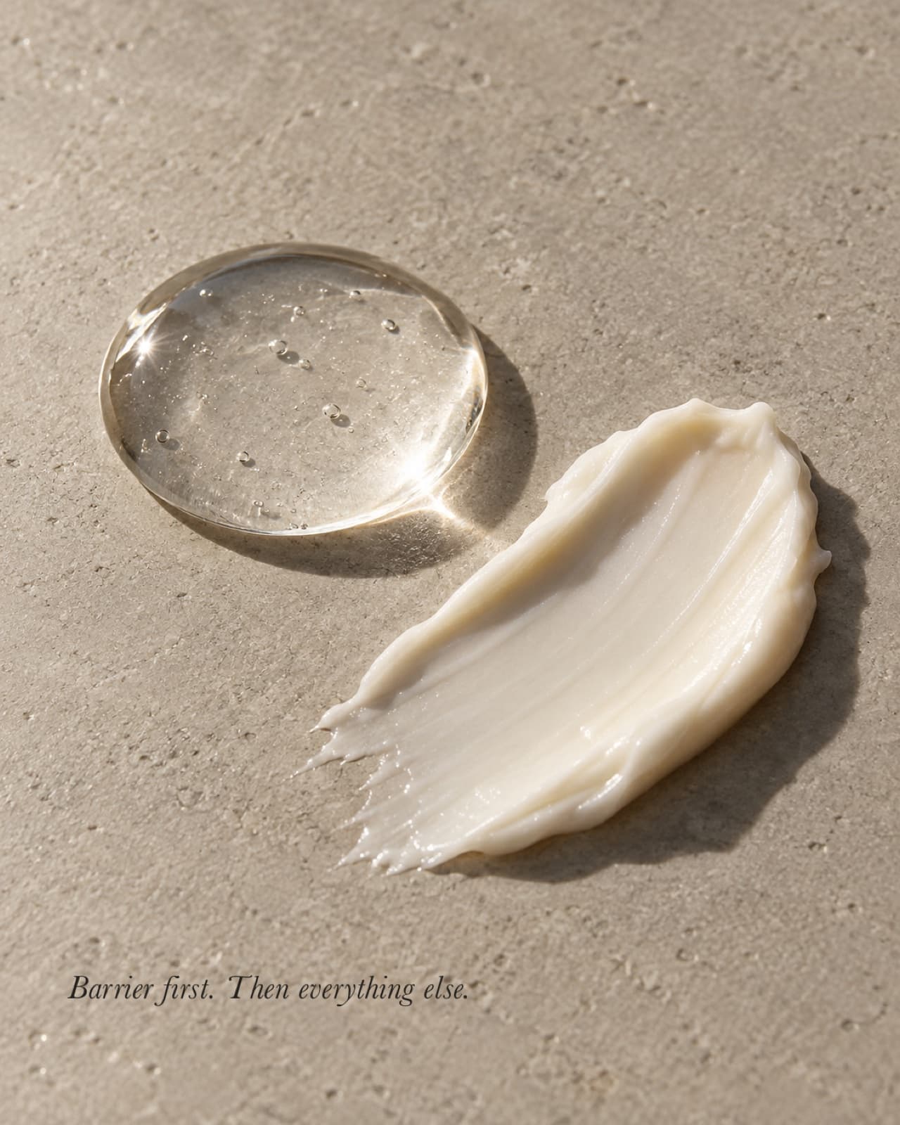 A bead of serum and a swatch of cream on a matte stone surface