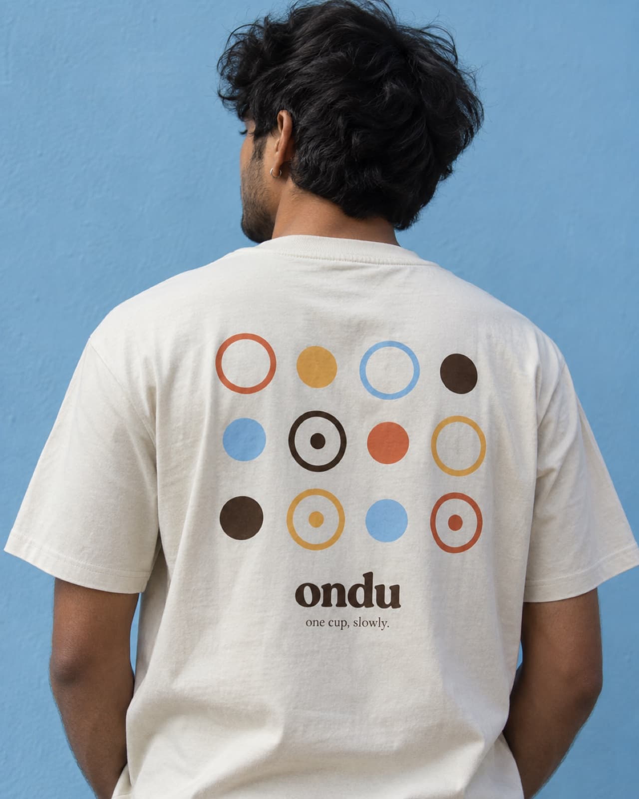 The back of a cream tee printed with the ring-and-dot pattern and the ondu wordmark