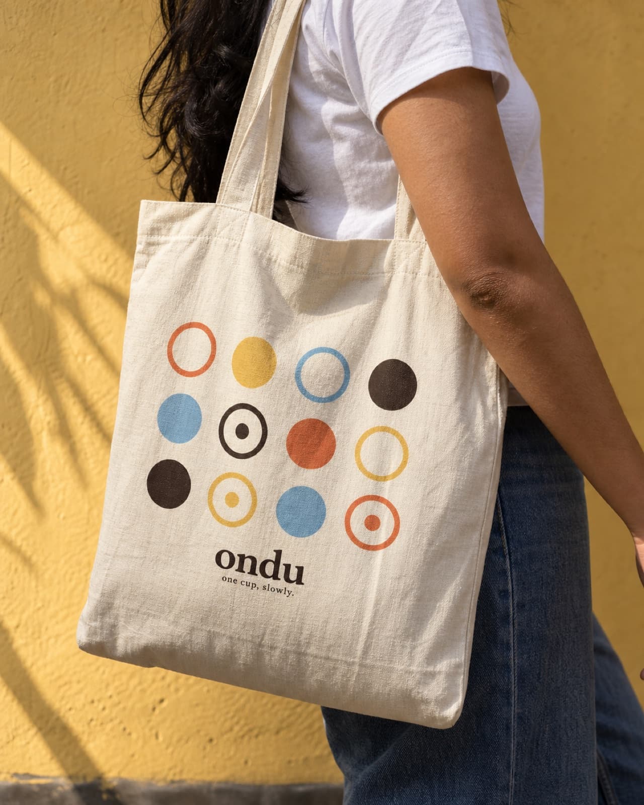 A cream tote bag printed with the ring-and-dot pattern and the ondu wordmark